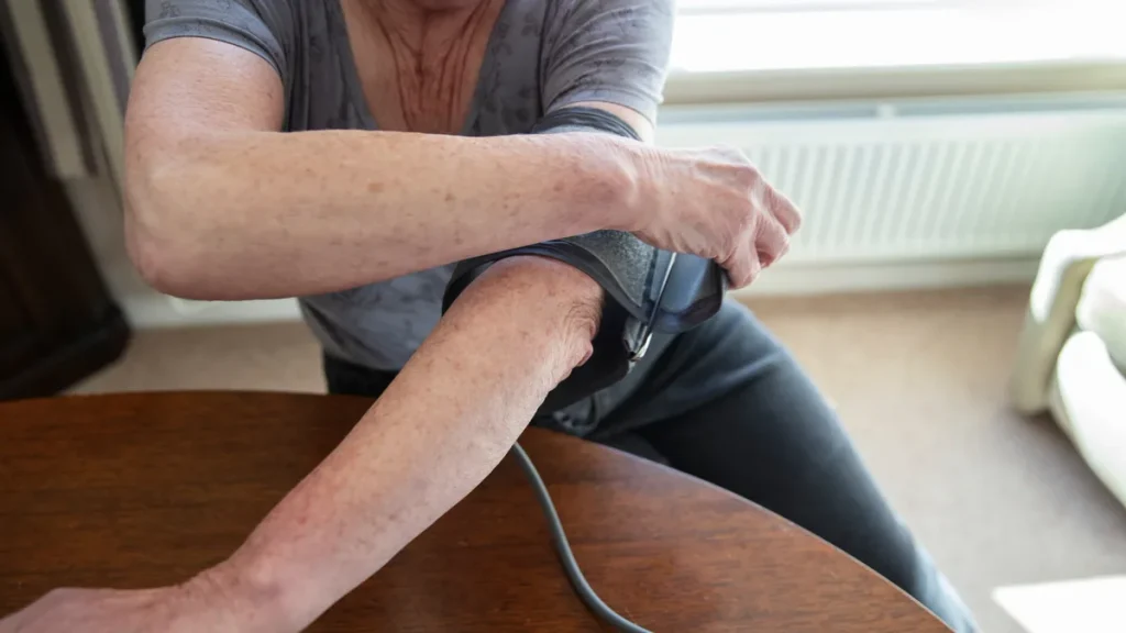 Persona se coloca el brazalete de un tensiómetro digital en el brazo para medir la presión arterial