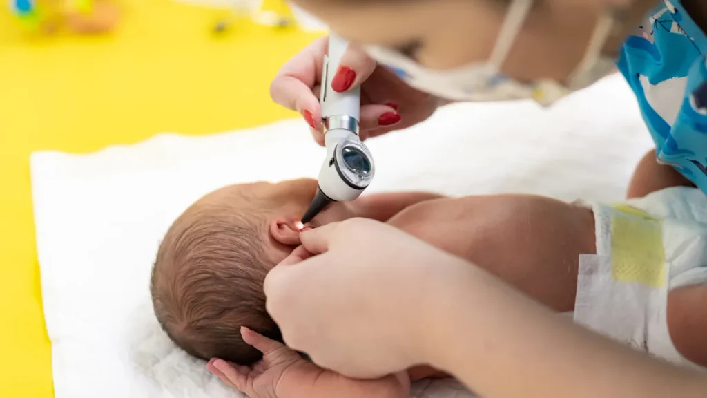 Pediatra con mascarilla explora a un bebé en consulta, una revisión clave ante la bronquiolitis en bebés