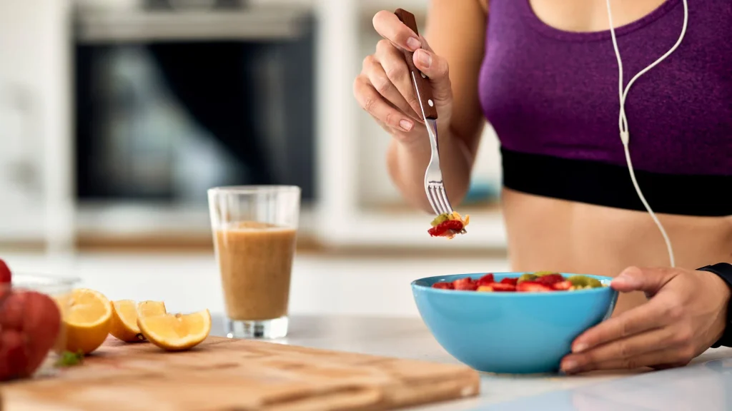 Mujer comiendo un bol de fruta para mostrar cómo comer sano y hacer ejercicio