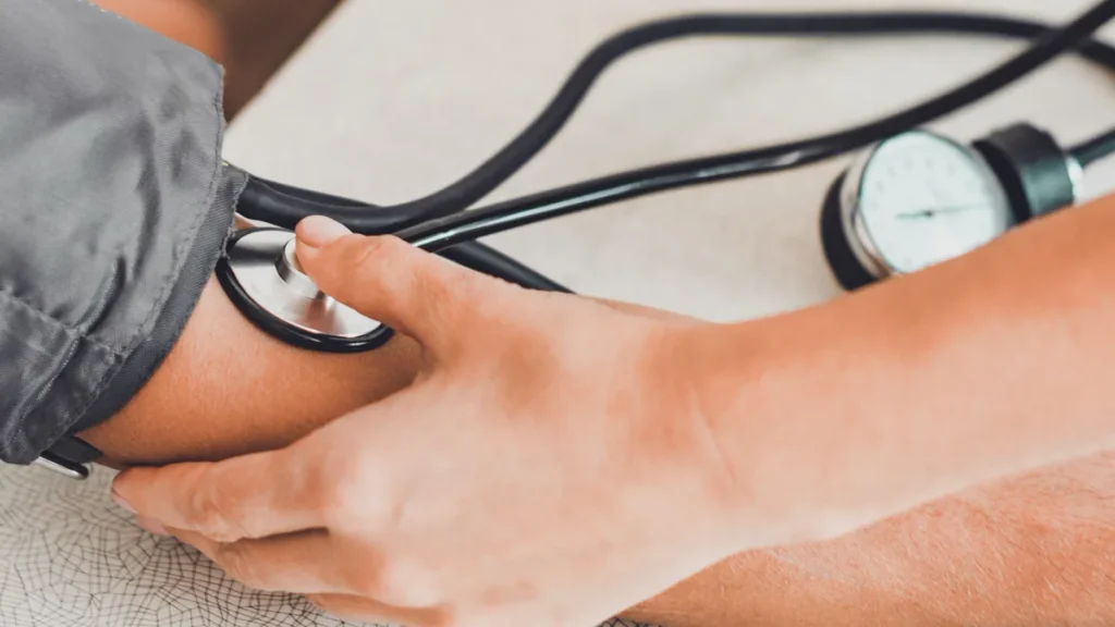 Médico toma la tensión en el brazo de un paciente para saber cómo bajar la tensión arterial