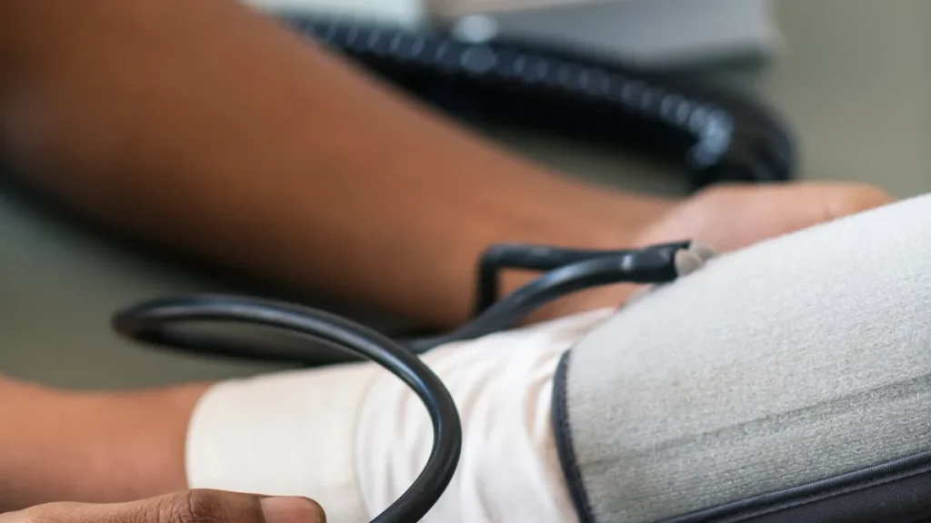 Manos pulsan la pera de un tensiómetro manual con el brazalete colocado en el brazo de un paciente