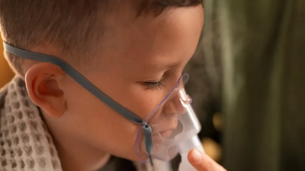 Niño con mascarilla de nebulización y una manta, durante los cuidados en casa de una infección respiratoria