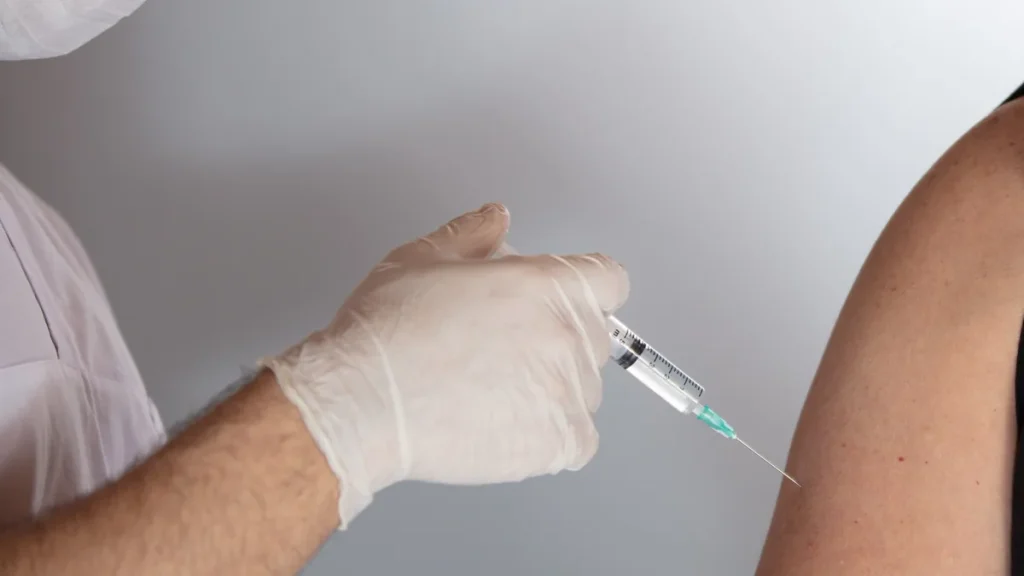 Por qué es importante vacunarse: profesional sanitario con guantes que aplica una vacuna en el brazo de un paciente