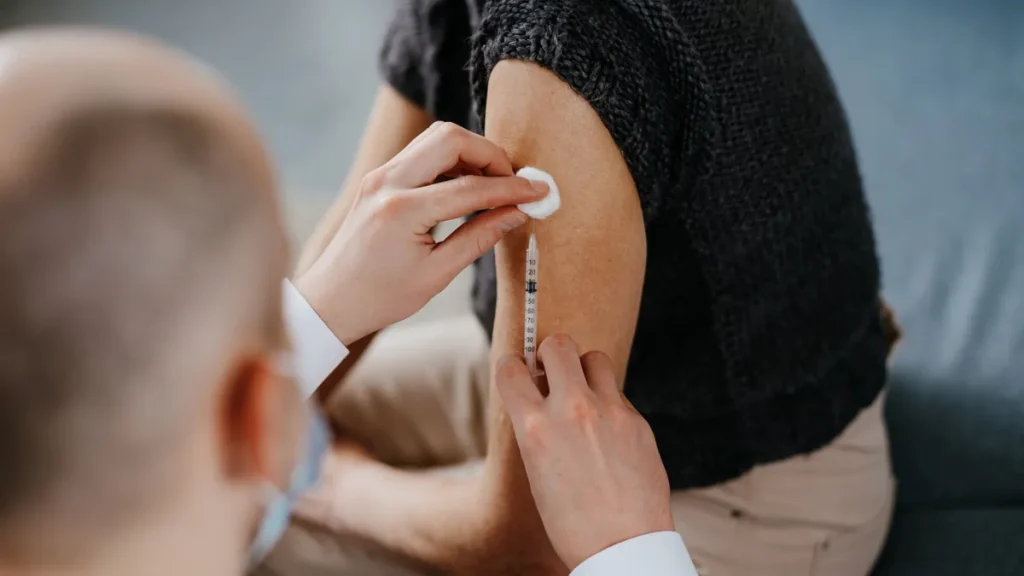 Médico que prepara la inyección en el brazo de un adulto durante la campaña de vacunación de la gripe