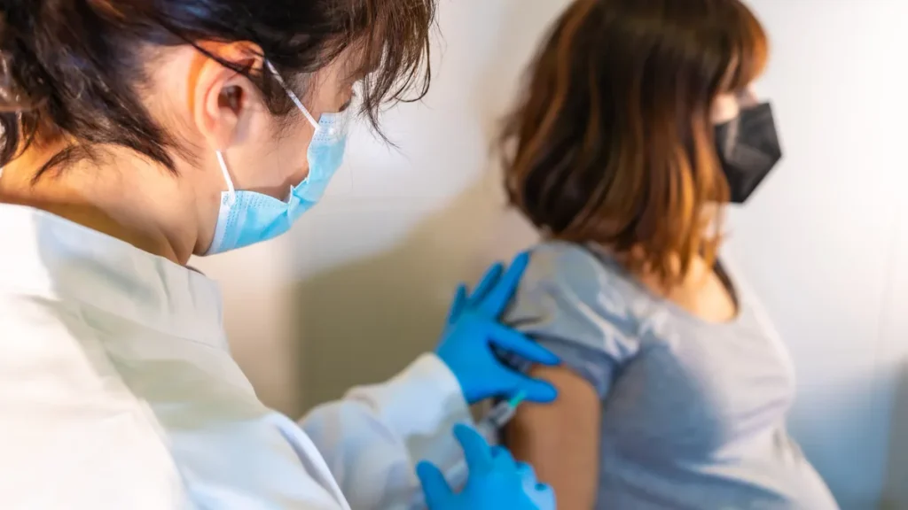 Médico que desinfecta con algodón el brazo de una paciente antes de ponerle una vacuna