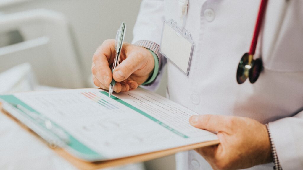 Médico firmando un formulario en una tabla portapapeles para el certificado médico náutico en Córdoba.